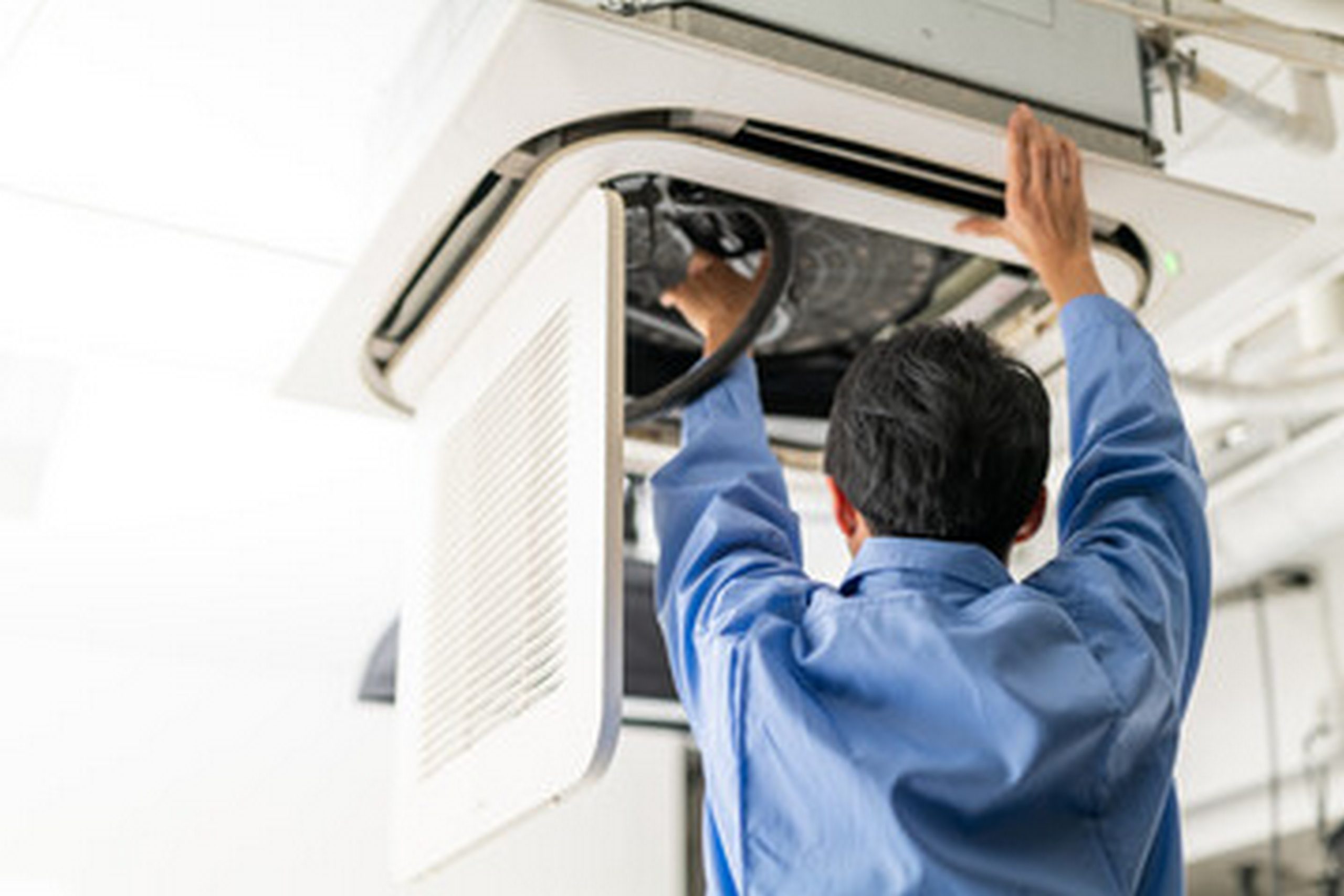 A professional technician performing a deep aircon chemical overhaul Singapore on a commercial ceiling cassette unit.