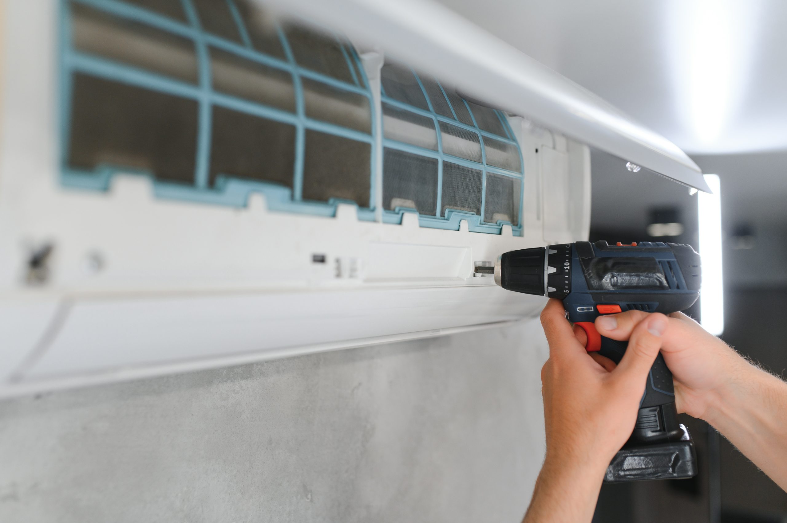Professional HVAC repairman performing a detailed disassembly of an indoor fan coil unit for a comprehensive maintenance check