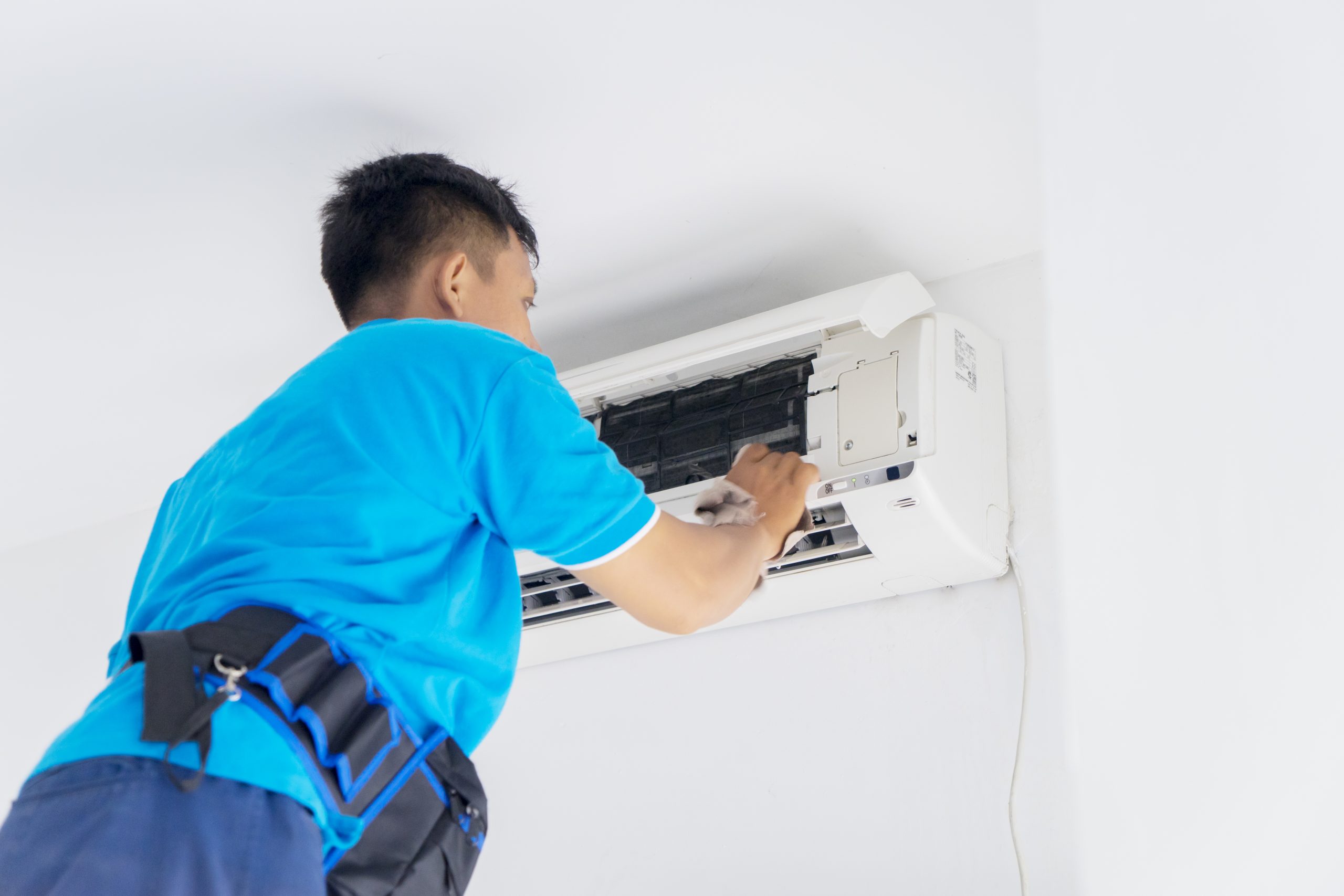 Expert air conditioner servicing in Singapore featuring the careful cleaning of an indoor split-unit by a trained technician