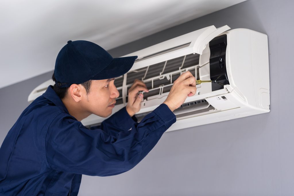 Aircon technician repairing and inspecting wall-mounted indoor air conditioner unit